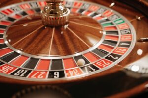 Una toma de ángulo bajo a nivel de la superficie muestra la base de madera de una ruleta en un casino, mientras la bola blanca se detiene en una ranura. Cómo el diseño de una mesa en vivo influye en la velocidad de decisión del jugador.