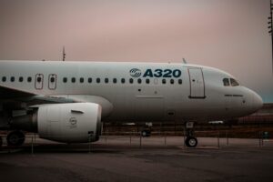 Primer plano lateral de un avión de pasajeros A320 de la empresa Airbus en pista, mostrando las puertas y ventanas del fuselaje, cuya producción se realiza en Querétaro, México.