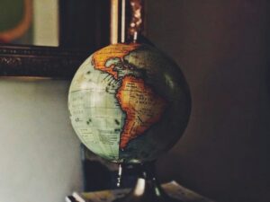 Un globo terráqueo antiguo ilumina el continente americano, mostrando a México, Estados Unidos y Brasil bajo una luz cálida sobre un fondo oscuro e íntimo.