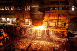A large industrial ladle pours incandescent molten metal inside a steel mill, generating intense golden sparks in a high-temperature steel manufacturing and heavy production environment. Effectiveness of Section 232 on Steel Products: Nucor’s Perspective.